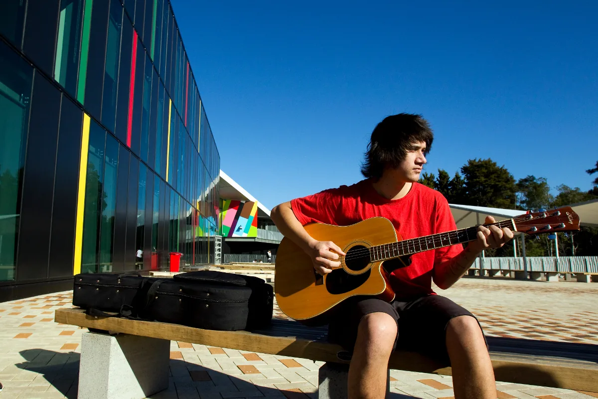 Student playing an acoustic guitar