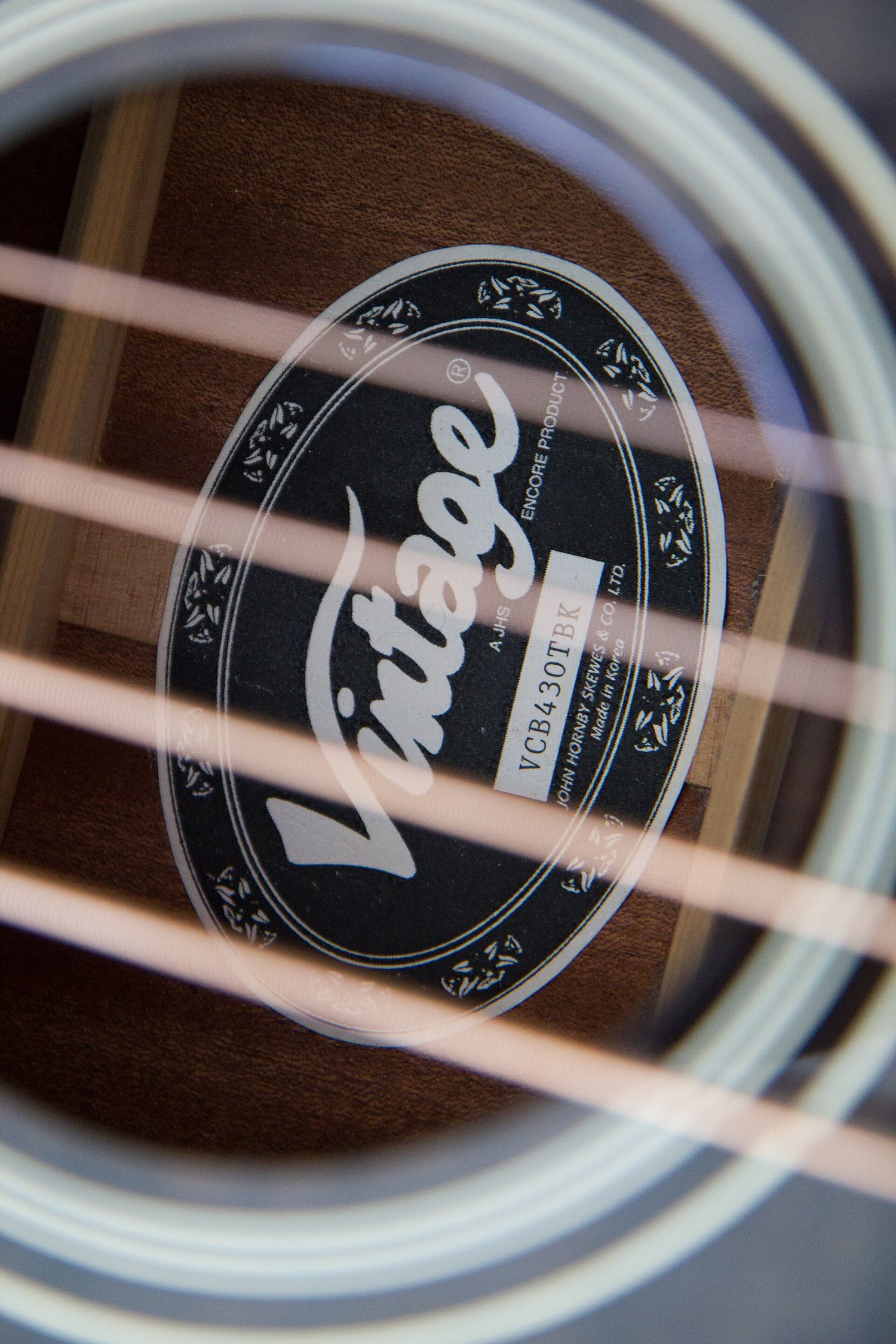 Étiquette noire visible à travers les cordes d’une guitare acoustique